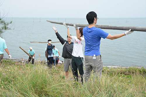 南華大學發起淨灘，以人龍方式共同傳送鰲鼓濕地西堤外側漂流竹木。