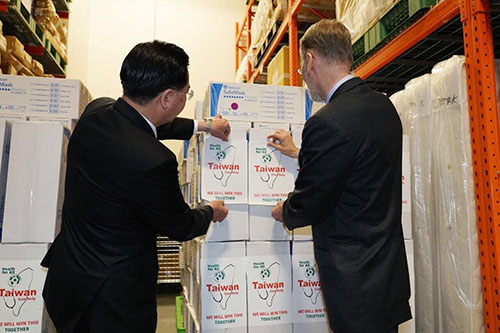外交部部長與酈英傑處長共同為在捐贈美國口罩紙箱貼上「Taiwan can help」之貼紙