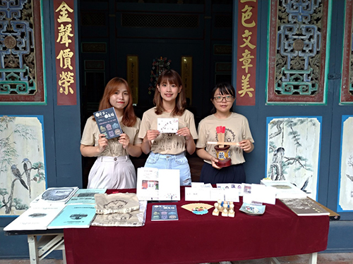 何品嫻(左)、李佩臻(中)、陳昱靜(右)同學，身著設計的紀念T恤展示體驗期間產出的手冊、導覽地圖等成果